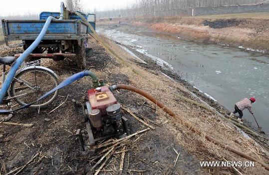 A farmer pumps water from a drying-up pond to water wheat fields at Yangzhuang Village in Linyi City, east China's Shandong Province, Feb. 8, 2011. [Xinhua]