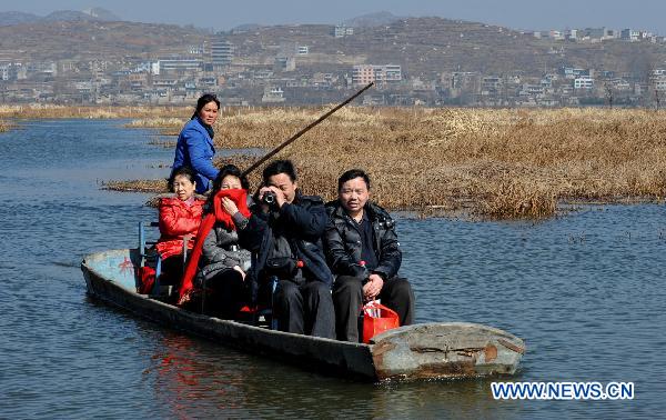 Tourists sail along a river inside a wetland park in Weining, southwest China&apos;s Guizhou Province, Feb. 6, 2011. With the coming of spring, tens of thousands of wild birds overwintering in the wetland became active again, attracting tourists during the traditional Chinese Spring Festival. 