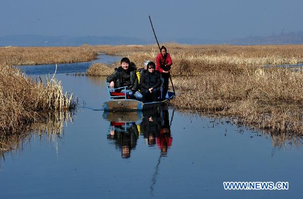 Tourists sail along a river inside a wetland park in Weining, southwest China&apos;s Guizhou Province, Feb. 6, 2011. With the coming of spring, tens of thousands of wild birds overwintering in the wetland became active again, attracting tourists during the traditional Chinese Spring Festival. [Xinhua]