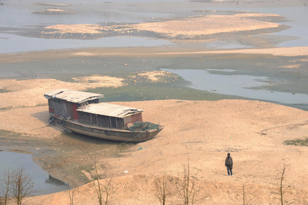 A fishing boat flounders on a dried-up part of Xiangjiang River in Changsha, capital of Central China's Hunan province, on Tuesday, Feb 8, 2011 after the lengthy drought that has affected much of the country lowered the level of the water. [Photo/Xinhua] 