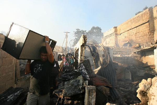 Residents retrieve their belongings from their burnt down homes in Quezon City, north of Manila, the Philippines, Feb. 8, 2011. Some 5,000 families were left homeless and investigators are still looking into what caused the fire. [Xinhua/Rouelle Umali]