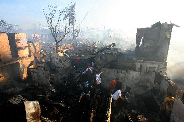 Residents look for reusable materials from their burnt down homes in Quezon City, north of Manila, the Philippines, Feb. 8, 2011. Some 5,000 families were left homeless and investigators are still looking into what caused the fire. (Xinhua/Rouelle Umali)