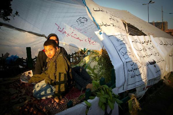 A boy wakes up at Tahrir Square in Cairo, capital of Egypt, Feb. 8, 2011. Demonstrations demanding resign of President Hosni Mubarak continued, though the new government approved 15-percent pay raise for government employees. 