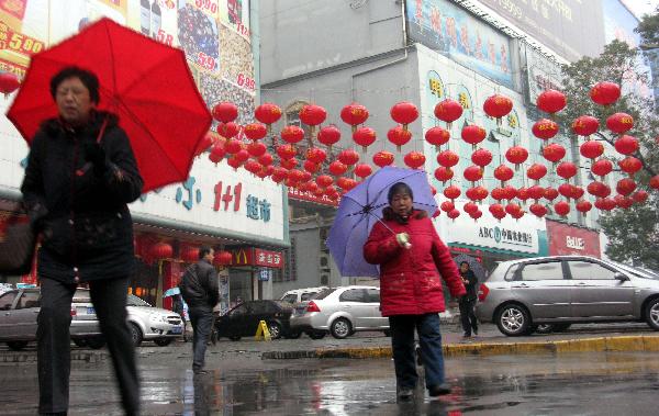 People walk in the rain in Shiyan, central China's Hubei Province, Feb. 9, 2011. Many places in China witnessed temperature drop due to strong cold air in recent days.