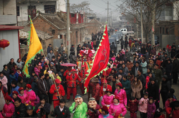 Local residents walk next a traditional Chinese wedding procession in Dong'an at the central province of Henan, February 9, 2011. [China Daily/Agencies]