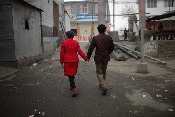 Rebecca Kanthor and Liu Jian walk along a empty street after their traditional Chinese wedding in Dong&apos;an at the central province of Henan, February 9, 2011. [China Daily/Agencies]