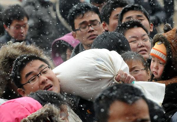 Crowds of passengers get into Zhengzhou Railway Station amid heavy snow during China&apos;s Spring Festival travel rush in Zhengzhou, capital of central China&apos;s Henan Province, Feb. 9, 2011. China&apos;s central area witnessed the first snow of this year on Wednesday. [Xinhua]