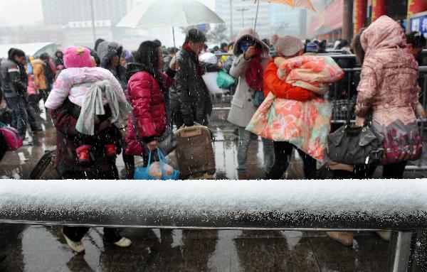 Passengers get into Zhengzhou Railway Station amid heavy snow during China&apos;s Spring Festival travel rush in Zhengzhou, capital of central China&apos;s Henan Province, Feb. 9, 2011. China&apos;s central area witnessed the first snow of this year on Wednesday. [Xinhua]