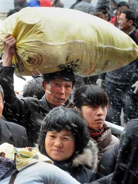 Two passengers check a train ticket while waiting for getting into Zhengzhou Railway Station amid heavy snow during China&apos;s Spring Festival travel rush in Zhengzhou, capital of central China&apos;s Henan Province, Feb. 9, 2011. China&apos;s central area witnessed the first snow of this year on Wednesday. [Xinhua]