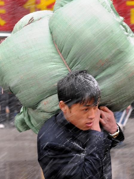 A man carries belongings on his way to Zhengzhou Railway Station amid heavy snow during China&apos;s Spring Festival travel rush which began on Jan. 19, in Zhengzhou, capital of central China&apos;s Henan Province, Feb. 9, 2011. China&apos;s central area witnessed the first snow of this year on Wednesday. [Xinhua]