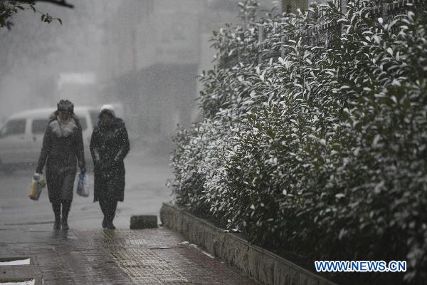 Citizens walk down a street in snow in Luoyang, central China&apos;s Henan Province, Feb. 9, 2011. Henan, one of the biggest farming provinces in China, saw long-awaited snowfalls Wednesday, which was expected to alleviate the prolonged drought that had ravaged the northern part of the country since last October.