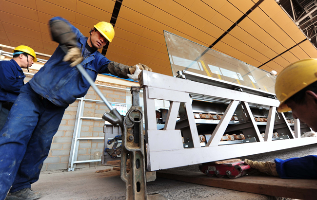 Photo taken on Feb. 10, 2011 shows a worker fixing an automatic walkway inside the new airport of Kunming, capital of south China&apos;s Yunnan Province. The investment of the new airport of Kunming has reached 14.26 billion RMB yuan, 75 percent of the project&apos;s total budget. [Xinhua] 