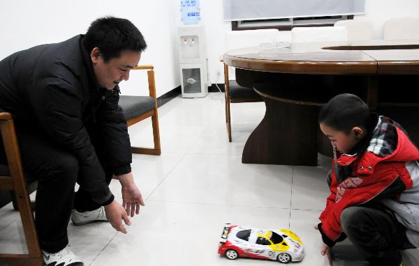 Peng Gaofeng and his lost son Peng Wenle play with an auto model in Pizhou, east China&apos;s Jiangsu Province, Feb. 9, 2011. A man who was reunited with his son three years after the boy was abducted said he would allow the woman whose husband stole the child to stay in touch with him. [Xinhua]