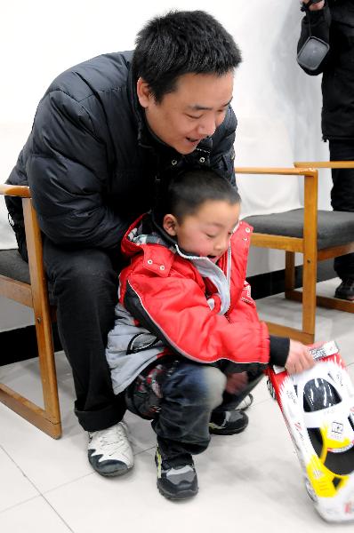 Peng Gaofeng watches his lost son Peng Wenle playing with an auto model in Pizhou, east China&apos;s Jiangsu Province, Feb. 9, 2011. [Xinhua]