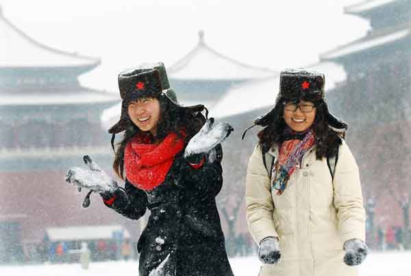 Tian Lin (left) and a friend frolic in front of the Forbidden City in central Beijing on Thursday, as the capital’s first snowfall this winter alleviated its worst drought in six decades. [China Daily]