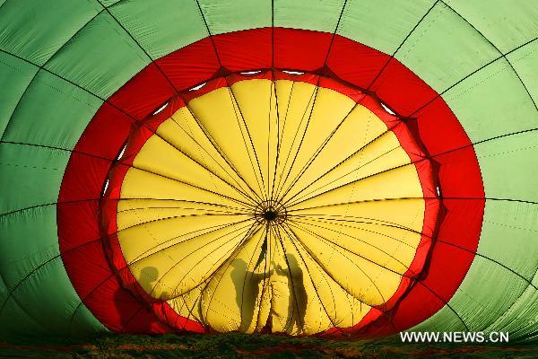 Hot-air balloon pilots cast their shadow as they prepare to inflate their balloon before their flight during the 16th Philippine International Hot-Air Balloon Fiesta at the Clark Freeport Zone in Pampanga, north of Manila, the Philippines, Feb. 10, 2011.