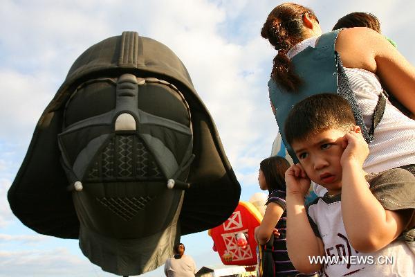 A boy covers his ears as he watches hot-air balloons floating in the sky during the 16th Philippine International Hot-Air Balloon Fiesta at the Clark Freeport Zone in Pampanga, north of Manila, the Philippines, Feb. 10, 2011.