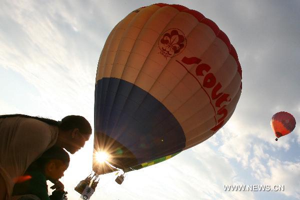 A mother and her son watch hot-air balloons float in the sky during the 16th Philippine International Hot-Air Balloon Fiesta at the Clark Freeport Zone in Pampanga, north of Manila, the Philippines, Feb. 10, 2011.