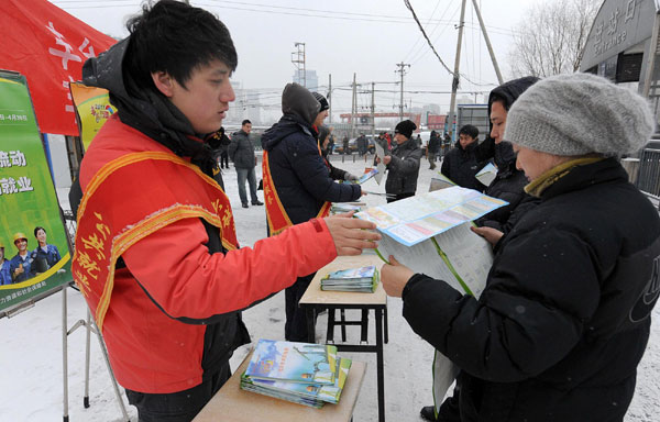 Staff members from employment service stations distribute handouts introducing basic information related to jobs at Liuliqiao terminal in Beijing, Feb 10, 2011. Since Feb 9, the first work day after the Spring Festival holiday, such services have been stationed at railway stations and major bus stations in Beijing, to help migrant workers get information about social security and protection of their rights. [Photo/Xinhua] 