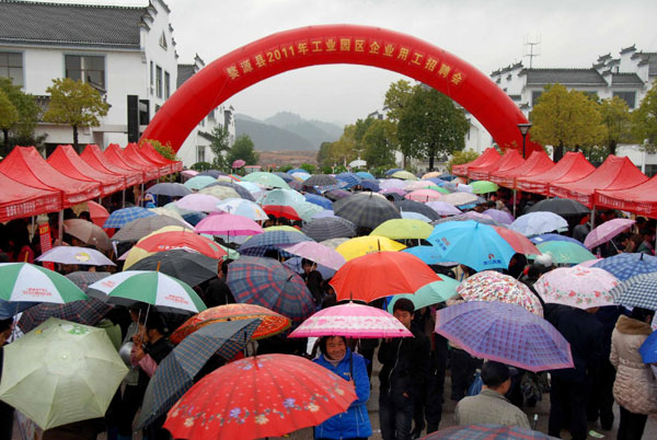 Migrant workers wait in the rain to get job information in Shangrao, east China's Jiangxi Province, Feb 10, 2011. The first job fair for migrant workers back to Wuyuan county, where 31 companies offered 6,120 job positions, attracted more than 10,000 job-hunters. [Photo/Xinhua] 