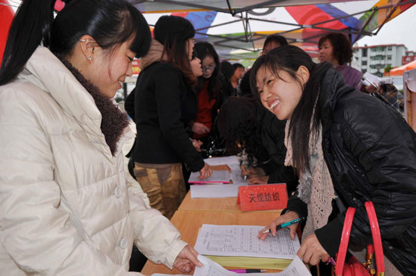 A migrant worker (Right) signs a work contract at a job fair in Fuzhou, east China's Jiangxi Province, Feb 10, 2011. More than 1,600 workers signed employment contracts that day. [Photo/Xinhua]