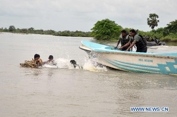 Sri Lankan soldiers help displaced people cross flooded road in the eastern district of Batticaloa, Sri Lanka, Feb. 10, 2011. At least 21 people have died and over 1.2 million affected by heavy monsoon showers that flooded most parts of the island&apos;s north, north central and eastern regions. Flooding in the same areas last month left 43 dead and drove over a million people from their homes. [Xinhua] 