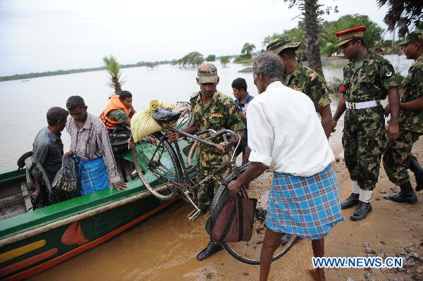 Sri Lankan soldiers help displaced people cross flooded road in the eastern district of Batticaloa, Sri Lanka, Feb. 10, 2011. 