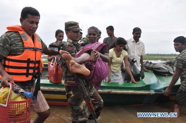 Sri Lankan soldiers help displaced people cross flooded road in the eastern district of Batticaloa, Sri Lanka, Feb. 10, 2011. 