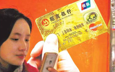 A girl reads a cell phone message in front of an ad for China Merchants Bank (CMB) in Shanghai. CMB is the only commercial bank chosen for a deposit rates liberalization trial.[China Daily]