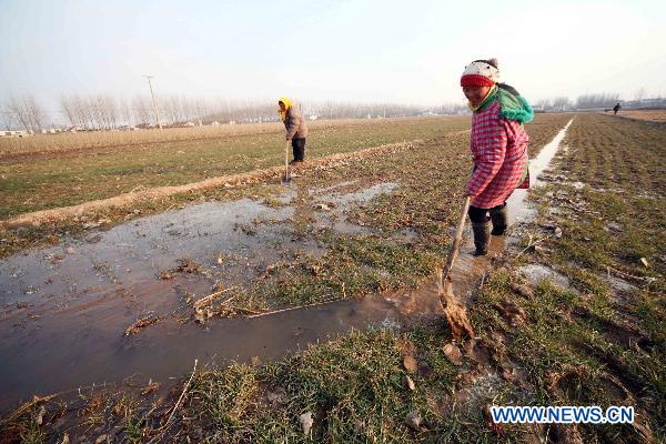 Farmers shovel channel water to a wheat field in Ganyu County, east China's Jiangsu Province, Feb. 14, 2011. Local government allocated 10 million yuan (1.52 million U.S. dollars) and dispatched more than 100 technicians to the farmlands for drought fight. [Xinhua]