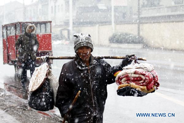 A resident carries daily commodities in snow in Nanjing, capital of east China&apos;s Jiangsu Province, Feb. 14, 2011. A snow shower fell on Jiangsu Monday.