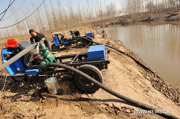 Farmers pump water from a river with tractor-mounted water pumps at Jishan County, north China&apos;s Shanxi Province, Feb. 14, 2011. The local government has dispatched eight technical support teams equipped with water pumps and tankers to help farmers with their anti-drought fight during the spring farming season. [Xinhua] 