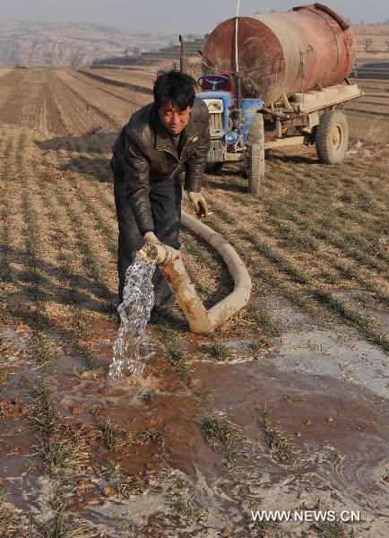 A farmer waters a wheat field with free water delivered by the local government at Jishan County, north China&apos;s Shanxi Province, Feb. 14, 2011. The local government has dispatched eight technical support teams equipped with water pumps and tankers to help farmers with their anti-drought fight during the spring farming season.