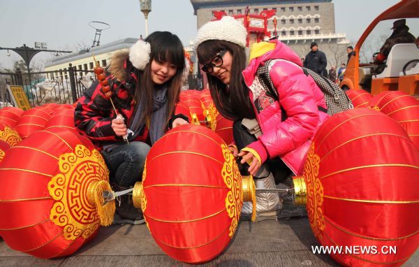 Two girls view a suite of lanterns, which is about to be hung up, at Qianmen Avenue in Beijing, capital of China, Feb. 15, 2011. A carnival began at the avenue Tuesday, including lantern show, dragon dances, Peking Opera performances, to celebrate the upcoming Lantern Festival which falls on Feb. 17, 2011. (Xinhua/Chen Xiaogen) (ly) 