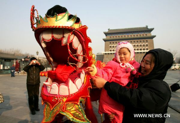 A child touches dragon head after a dragon dance performance at Qianmen Avenue in Beijing, capital of China, Feb. 15, 2011. A carnival began at the avenue Tuesday, including lantern show, dragon dances, Peking Opera performances, to celebrate the upcoming Lantern Festival which falls on Feb. 17, 2011. (Xinhua/Zhao Bing) (ly) 