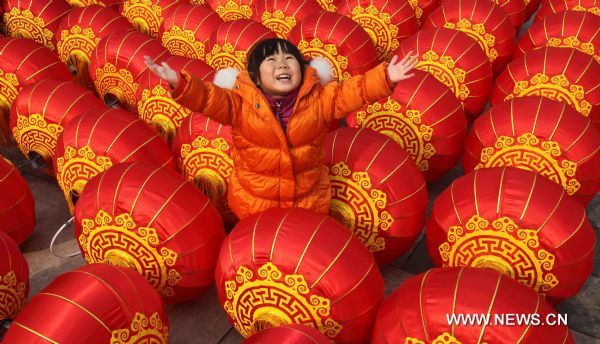 A girl poses for photos with lanterns, which are about to be hung up, at Qianmen Avenue in Beijing, capital of China, Feb. 15, 2011. A carnival began at the avenue Tuesday, including lantern show, dragon dances, Peking Opera performances, to celebrate the upcoming Lantern Festival which falls on Feb. 17, 2011. (Xinhua/Chen Xiaogen) (ly) 