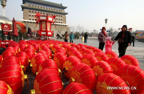 Tourists walk past red lanterns, which are about to be hung up, at Qianmen Avenue in Beijing, capital of China, Feb. 15, 2011. A carnival began at the avenue Tuesday, including lantern show, dragon dances, Peking Opera performances, to celebrate the upcoming Lantern Festival which falls on Feb. 17, 2011. [Xinhua/Zhao Bing]