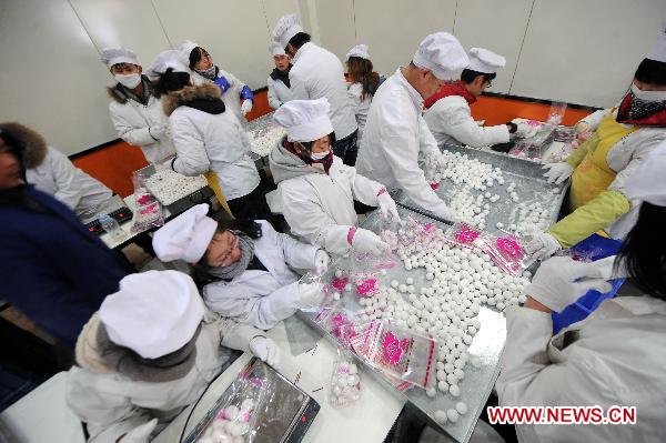 Staff members make Yuanxiao (glutinous rice flour dumpling with sweetened stuffing) at a food shop in Taiyuan, capital of north China's Shanxi Province, Feb. 15, 2011. Yuanxiao is eaten in China's Lantern Festival, a traditional festival for family reunion. [Fan Minda/Xinhua]