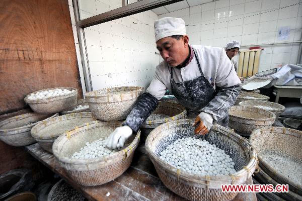 A staff member makes Yuanxiao (glutinous rice flour dumpling with sweetened stuffing) at a food shop in Taiyuan, capital of north China's Shanxi Province, Feb. 15, 2011. Yuanxiao is eaten in China's Lantern Festival, a traditional festival for family reunion. [Fan Minda/Xinhua]