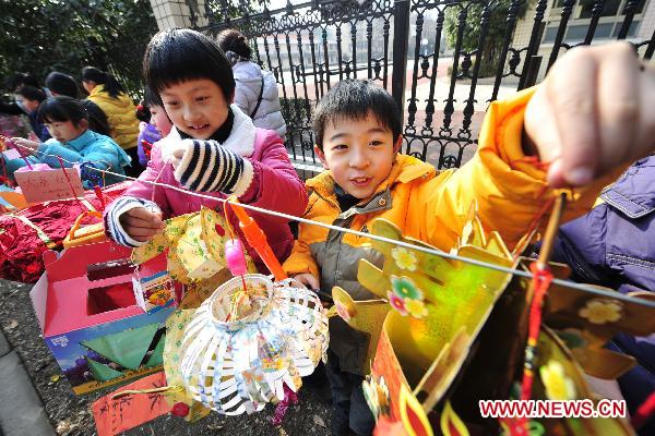 Pupils hang lanterns made by themselves with wasted materials at the gate of Qiushi Primary School in Hangzhou, capital of east China's Zhejiang Province, Feb. 15, 2011. A lantern carnival in the theme of low carbon will be held in the school to celebrate the Lantern Festival that falls on Feb. 17, 2011. Some 800 low carbon lanterns have already been submitted up to now. [Li Zhong/Xinhua]