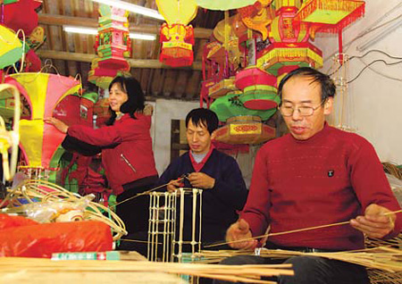 Cao Shuzhen (left) and her brothers, Cao Zhixiong (center) and Cao Zhimeng, are making lanterns at their family workshop in Quanzhou, Fujian province. Cao Shuzhen is a provincial-level master of this art form. [China Daily] 