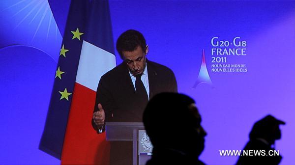 People watch French President Nicolas Sarkozy delivering a keynote speech through a TV screen at the G20 press center in Paris, France, Feb. 18, 2011. The 2-day G20 meeting of Finance Ministers and Central Bank Governors opened here on Friday.