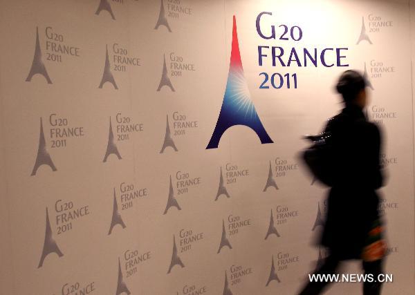 A woman walks past a poster of the G20 meeting of Finance Ministers and Central Bank Governors at the G20 press center in Paris, France, Feb. 18, 2011. The 2-day G20 meeting of Finance Ministers and Central Bank Governors opened here on Friday. 