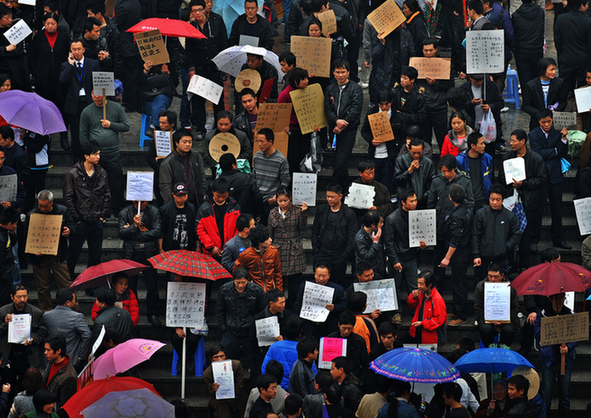 Recruiters hold up boards advertising jobs as they seek migrant workers at a job market.