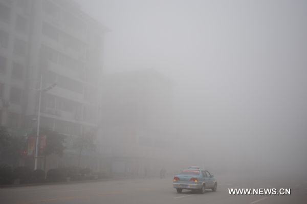 A car runs on the fog shrouded street in Shangrao, east China&apos;s Jiangxi Province, Feb. 20, 2011. Shangrao witnessed heavy fog on Sunday. [Xinhua]