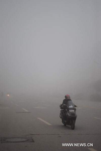 A citizen rides on the fog shrouded street in Shangrao, east China&apos;s Jiangxi Province, Feb. 20, 2011. Shangrao witnessed heavy fog on Sunday. [Xinhua]