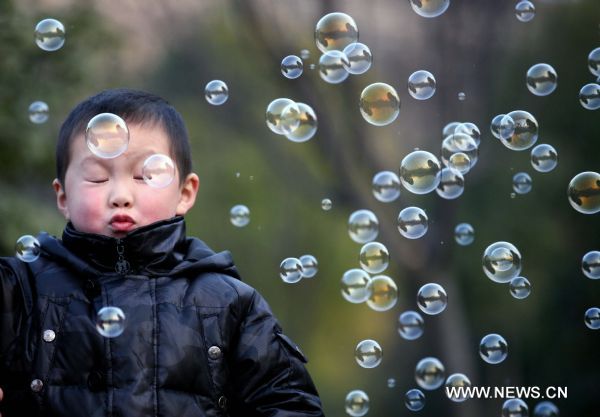 A boy reacts near bubbles in Xuanwu Lake Park in Nanjing, capital of east China&apos;s Jiangsu Province, Feb. 20, 2011. As the temperature rose on Sunday, local residents went outdoors to enjoy warm spring weather in Nanjing.