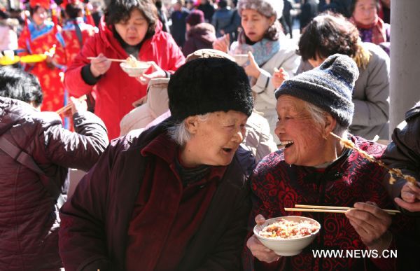 Two elderly talk and smile during the Lianqiao Festival celebration in Yangshudixia Village of Beijing, capital of China, Feb. 18, 2011.