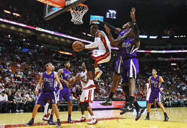 Miami Heat's Dwyane Wade (C), leaps past the defense of Sacramento Kings Jermaine Taylor (3) and Jason Thompson (32) during first quarter in NBA basketball action in Miami, Florida February 22, 2011. Miami Heat won 117-97. (Xinhua/Reuters Photo)