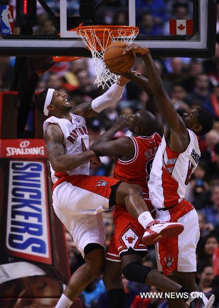 Luol Deng(C) of Chicago Bulls is blocked by James Johnson(L) and Amir Johnson of Toronto Raptors during their NBA game at Air Canada Centre in Toronto, Canada, Feb.23, 2011. Raptors won 118-113. (Xinhua/Zou Zheng) 